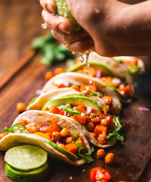 woman squeezing lime juice over tacos