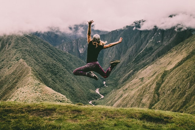 Woman jumping in green mountains